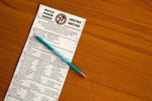 Build Your Burger order sheet and pencil on a wooden table