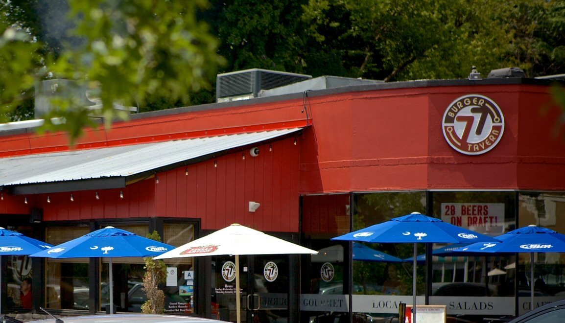 Burger Tavern 77 storefront on Devine Street in Columbia, SC with blue patio umbrellas